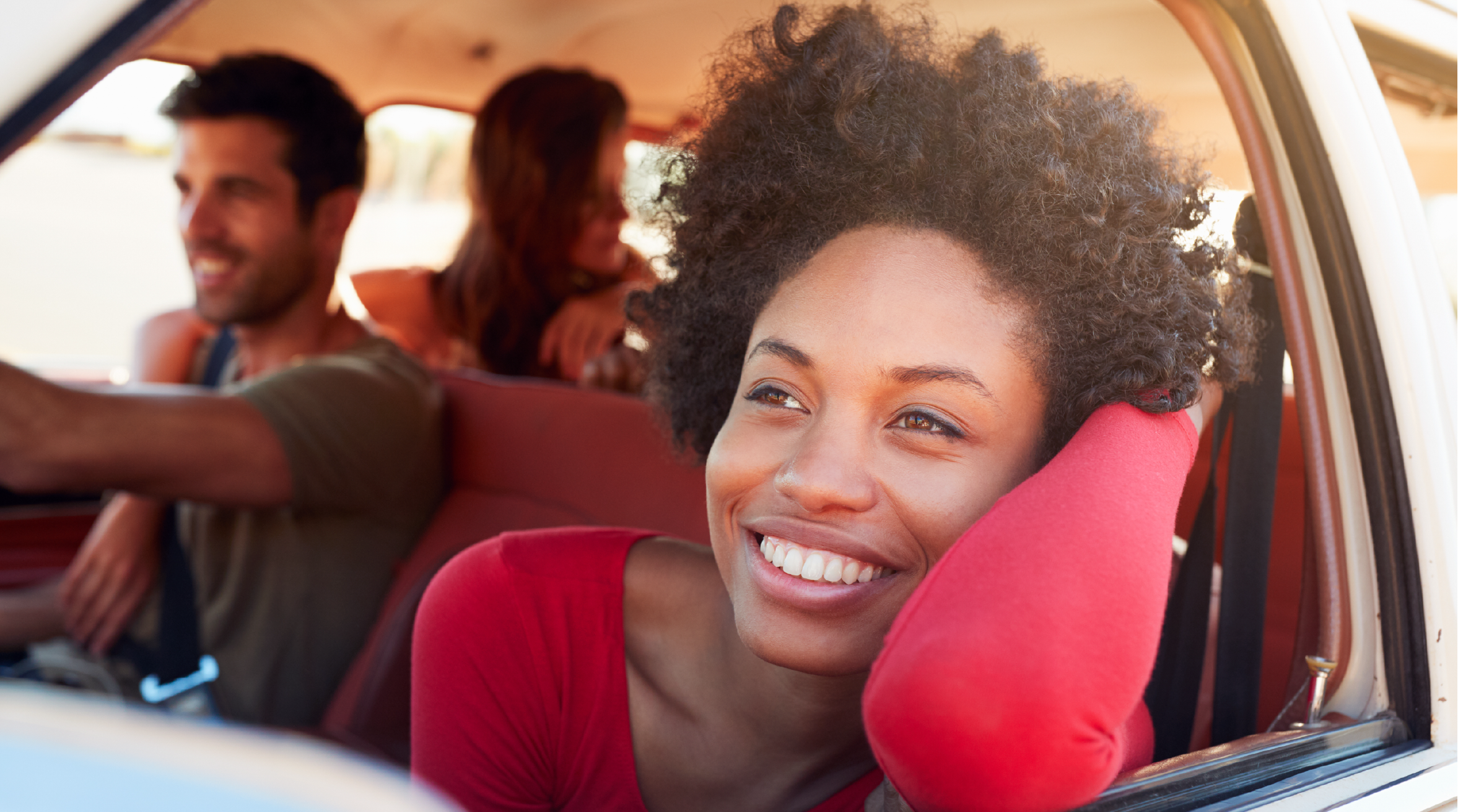 A group of people in a car with one woman in the foreground smiling